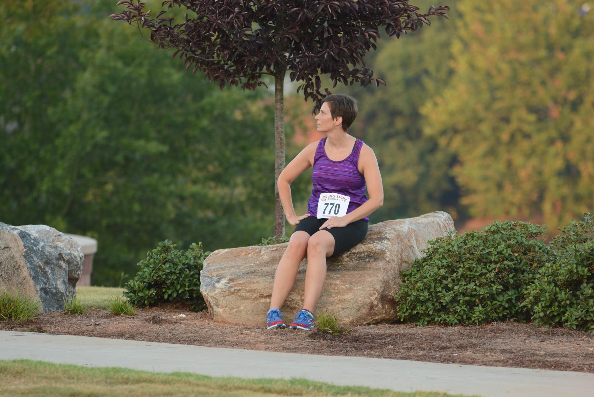 A runner sitting on a rock.